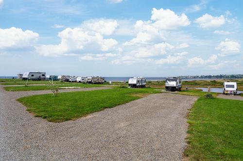 RV Space showing the large, gravel parking area surrounded by grass with views of the beach.